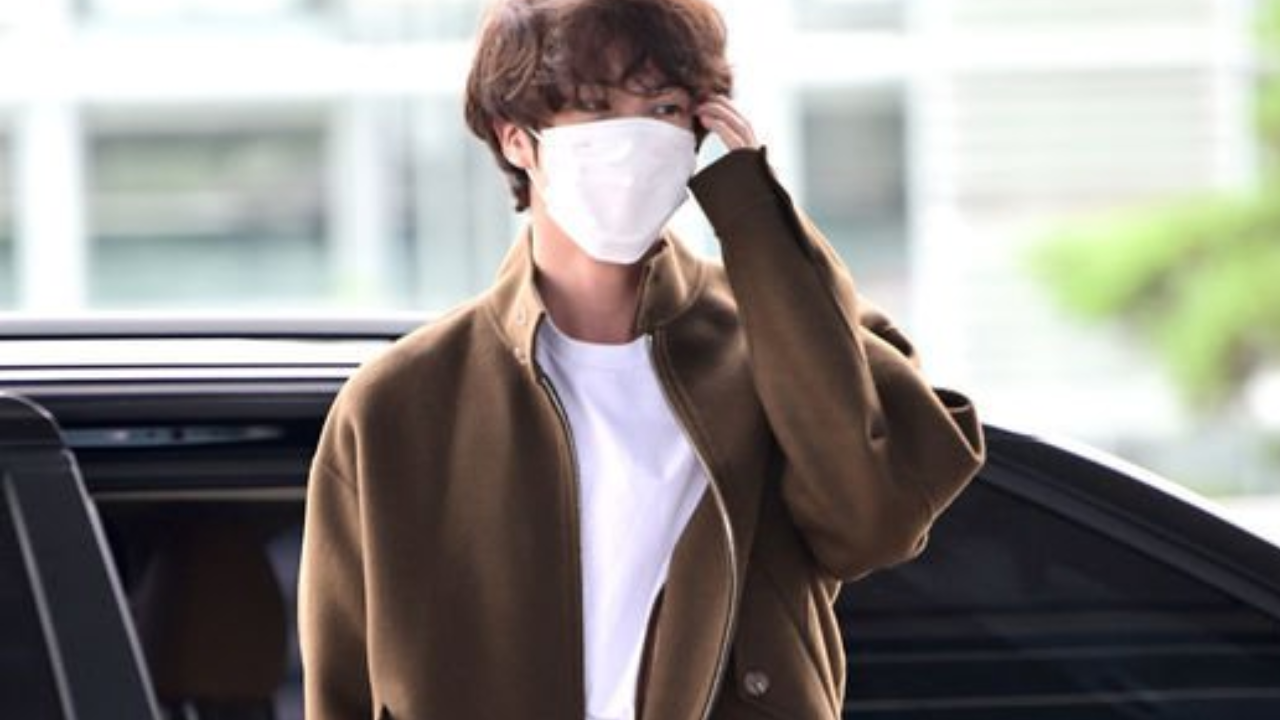 BTS' Jin waves for cameras at airport